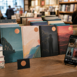 Bookstore display of trending novels beside a smartphone showing a generic short-form video feed